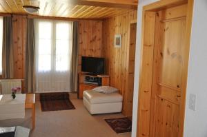 a living room with wooden walls and a television at FERIENWOHNUNGEN Chalet Hohturnen in Grindelwald