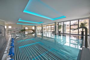 a large swimming pool with blue lights in a building at Hotel SOREA URÁN in Vysoke Tatry - Tatranska Lomnica.