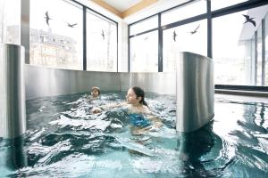 two people in a pool with birds in the water at Hotel SOREA URÁN in Tatranská Lomnica