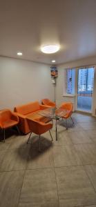 a waiting room with orange chairs and a glass table at Family apartment 2 rooms in Kharkiv