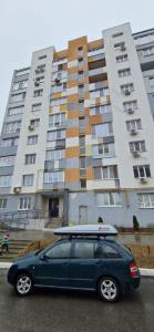 a car parked in front of a building with a surfboard on top at Family apartment 2 rooms in Kharkiv