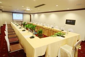 a conference room with a long table with chairs and a screen at Thumrin Hotel in Trang