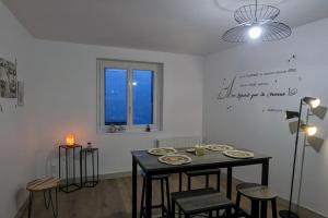 ein Esszimmer mit einem Tisch, Stühlen und einem Fenster in der Unterkunft Zen Home - appartement jusqu'à 4 voyageurs in Nantua