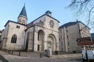 una vecchia chiesa in pietra con una torre dell'orologio e un cartello stradale di Zen Home - appartement jusqu'à 4 voyageurs a Nantua