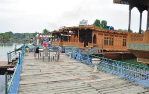 Alif Laila Group of Houseboats, Srinagar في سريناغار: رصيف خشبي مع مطعم على الماء