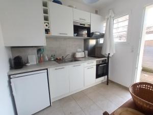 una cocina con armarios blancos y fregadero en Pyla-sur-mer maison 2 chambres et jardin - à 400m des plages en La Teste-de-Buch