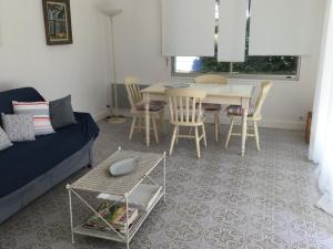 un soggiorno con divano, tavolo e sedie di Pyla-sur-mer maison 2 chambres et jardin - à 400m des plages a La Teste-de-Buch