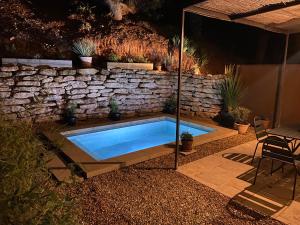 einen Pool in einem Garten mit einer Steinmauer in der Unterkunft Mas du Clos , Tilleul in Roussillon