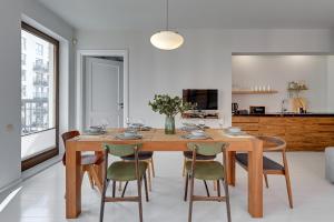 comedor con mesa de madera y sillas en Downtown Apartments Riverside & Parking Szafarnia Street, en Gdansk