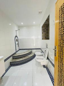 a white bathroom with a toilet and a sink at Hotel Palace tanger in Tangier