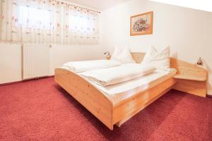 Cama de madera en habitación con alfombra roja en Ferienhaus Ennsling en Haus