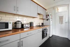 cocina con armarios blancos y encimera de madera en Alross Room with Breakfast en Londres