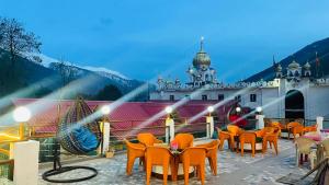 a restaurant with orange chairs and a building at Hotel Hilltop At Mall Road Manali With Open Terrace in Manāli