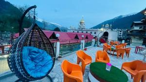 a patio with orange chairs and tables and a swing at Hotel Hilltop At Mall Road Manali With Open Terrace in Manāli