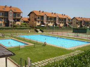 ein großer Pool mit Leuten, die mit Gebäuden darin schwimmen in der Unterkunft Apartamento Vistas Rovacias in Comillas