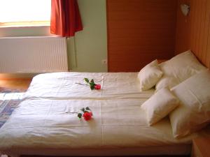 Una cama blanca con dos flores encima. en Lunczer Vendégház, en Mosonmagyaróvár