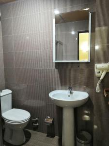 a bathroom with a sink and a toilet and a mirror at Hotel My Rose in Batumi