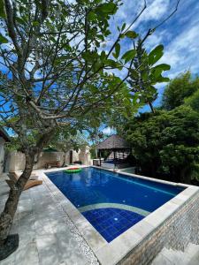 a swimming pool with a tree and a gazebo at Villa Neshama in Canggu
