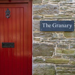 a red door and a sign on a stone wall at Forss House in Thurso