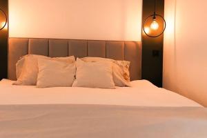 uma cama com almofadas brancas e duas luzes em The Modern Lodge em Skopje