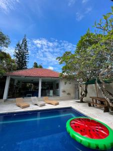 a pool with a red and green object in front of a house at Villa Neshama in Canggu