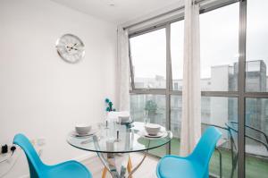 uma sala de jantar com uma mesa de vidro e cadeiras azuis em Stylish Apartment Close to London Bridge em Londres