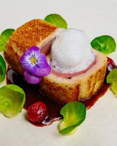 un trozo de pan con una flor púrpura en la parte superior en Adler Schiltach Boutique Hotel und Restaurant, en Schiltach 11 fotos más