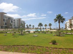 een park met palmbomen en een zwembad bij Superbe appartement vue sur mer in Sale