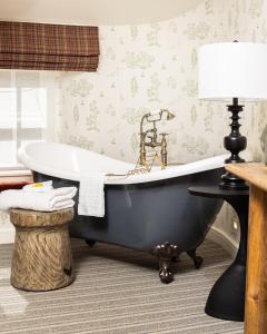 a bath tub in a bathroom with a lamp and wallpaper at The Dalesman Country Inn in Sedbergh