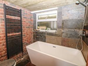 een badkamer met een wit bad en een bakstenen muur bij Compton Lodge in Buxton