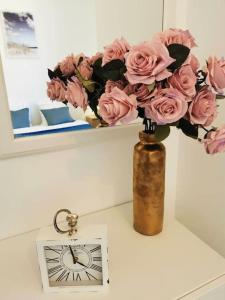 un vaso pieno di rose rosa, seduto accanto a un orologio. di Élégant duplex proche du centre-ville a Miramas