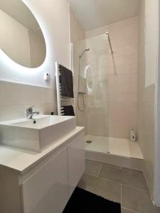 La salle de bains blanche est pourvue d'un lavabo et d'une douche. dans l'établissement Élégant duplex proche du centre-ville, à Miramas