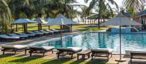 a swimming pool with lounge chairs and umbrellas at Azuri Homes Malindi, Stylish 1 bedroom beach front villa in Malindi