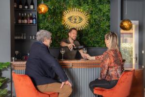 a man pouring a woman a glass of wine at a bar at Hôtel La Perna in Pernes-les-Fontaines