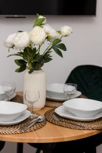 a table with white plates and a vase of roses at Metro Bemowo Apartment by Renters in Warsaw