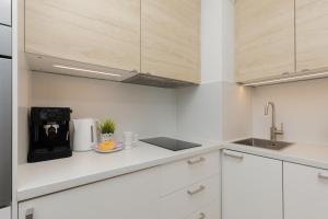 a kitchen with white cabinets and a coffee maker at Metro Bemowo Apartment by Renters in Warsaw