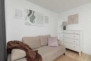 a white living room with a couch and a dresser at Metro Bemowo Apartment by Renters in Warsaw
