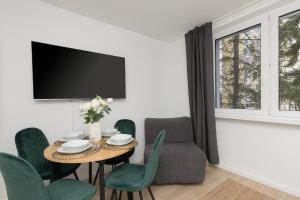 a living room with a table and chairs and a tv at Metro Bemowo Apartment by Renters in Warsaw