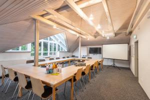 a conference room with a long table and chairs and a whiteboard at Hössensportzentrum in Westerstede +37 photos