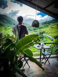 un uomo in piedi su un balcone con tavolo e vista di Levon Boutique Hotel a Ella