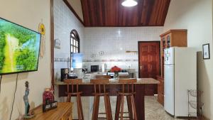 a kitchen with a counter with stools and a refrigerator at Big Beach Casa Temporada in Mangaratiba