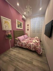 a bedroom with a bed with pink walls and a chandelier at Casa Vacanza Ginevra in Genoa