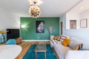 a living room with a couch and a green wall at Florentine Furnished flat in Annecy