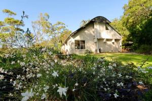 an old white barn with a field of flowers at Maleny-Montville Cottages in Balmoral Ridge