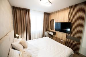 ein Hotelzimmer mit einem Bett und einem Flachbildfernseher in der Unterkunft Mountain Retreat-Modern 1BR w/ Fireplace & Parking in Braşov