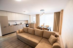 a living room with a couch and a table and a kitchen at Mountain Retreat-Modern 1BR w/ Fireplace & Parking in Braşov