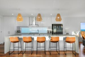 a kitchen with a counter with orange chairs in it at Luxurious Terrace Hideaway with a Heated Pool in Ocean Grove