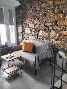 un sofá en una habitación con una pared de piedra en Stones By Syros Bnb, en Ermoupoli