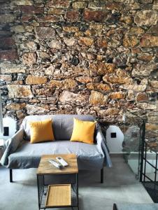 a living room with a stone wall with a couch at Stones By Syros Bnb in Ermoupoli