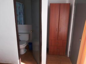 a bathroom with a toilet and a wooden door at Residencial Las Palmeras in Iquique